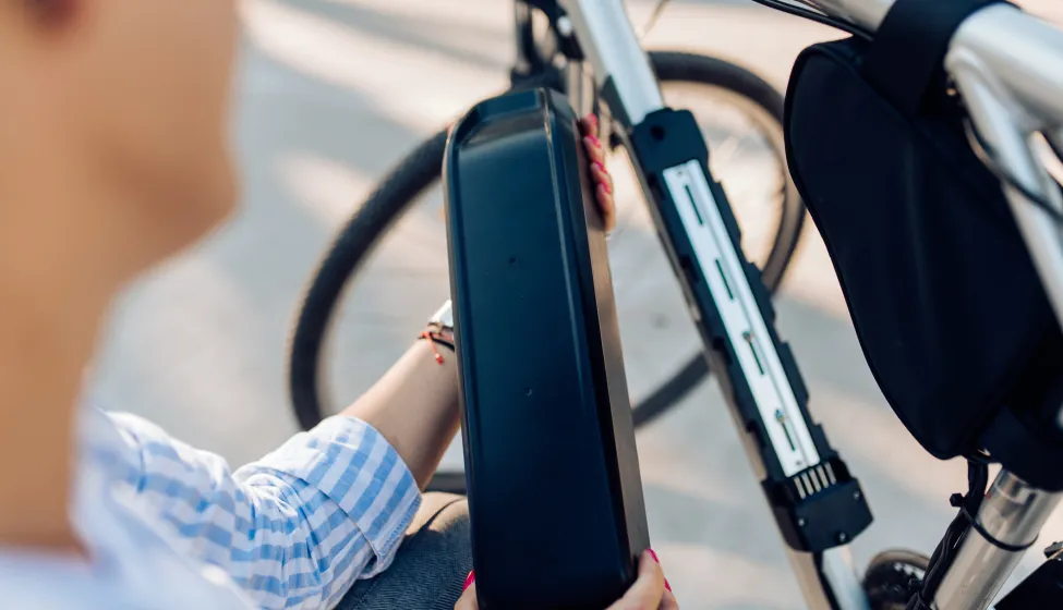 Mid adult woman charging her electric bicycle on her way to work.