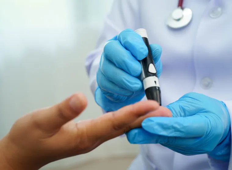 Asian woman self testing to check blood sugar level diabetes by digital lancet on finger at home.